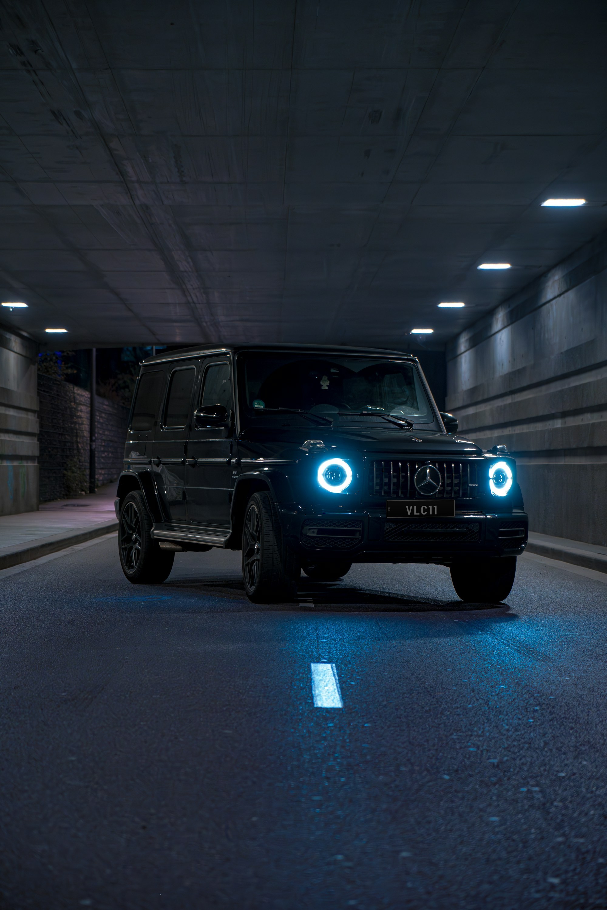 Black Mercedes-AMG G 63 with glowing headlights in a tunnel